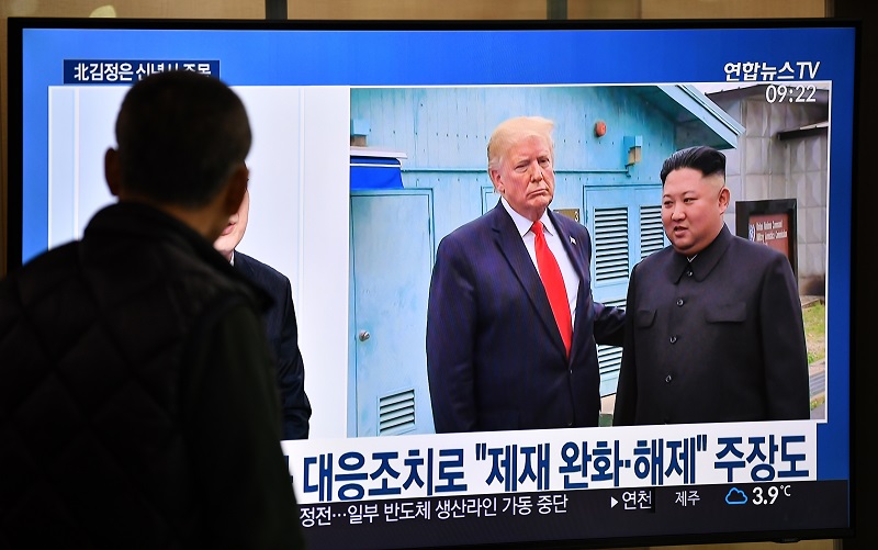 A man watches a television news program showing file footage of a meeting between US President Donald Trump and North Korean leader Kim Jong Un at the truce village of Panmunjom, at a railway station in Seoul on January 1, 2020. (AFP)