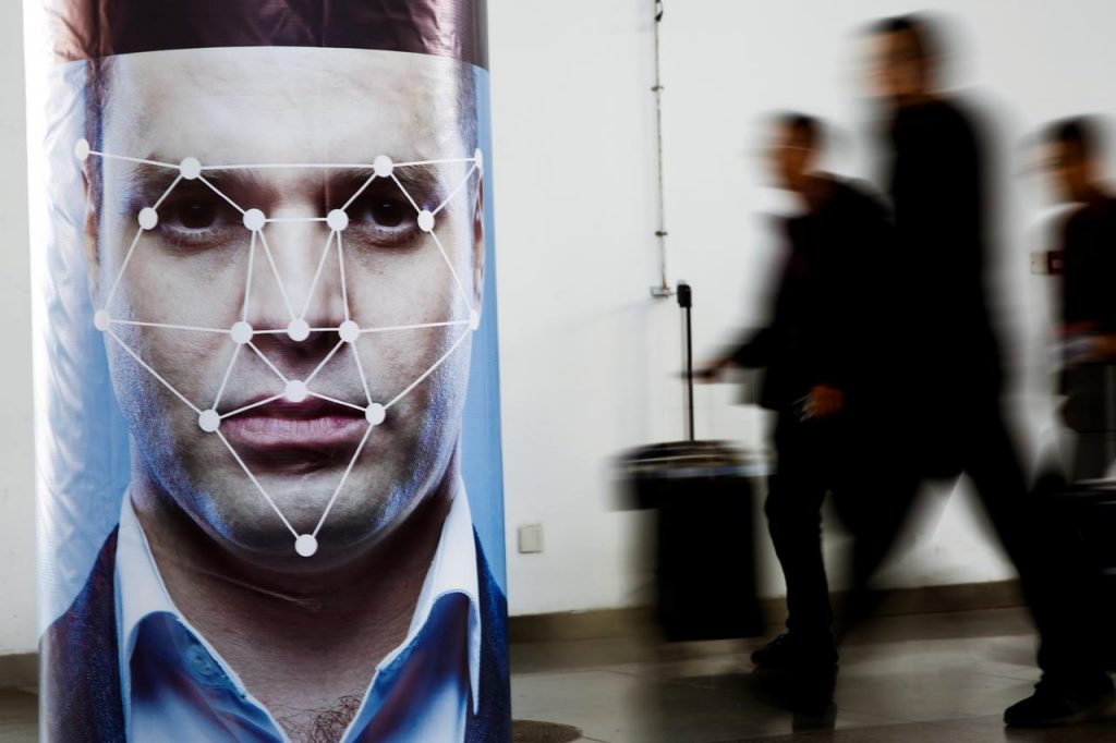 People walk past a poster simulating facial recognition software at the Security China 2018 exhibition on public safety and security in Beijing. (Reuters)