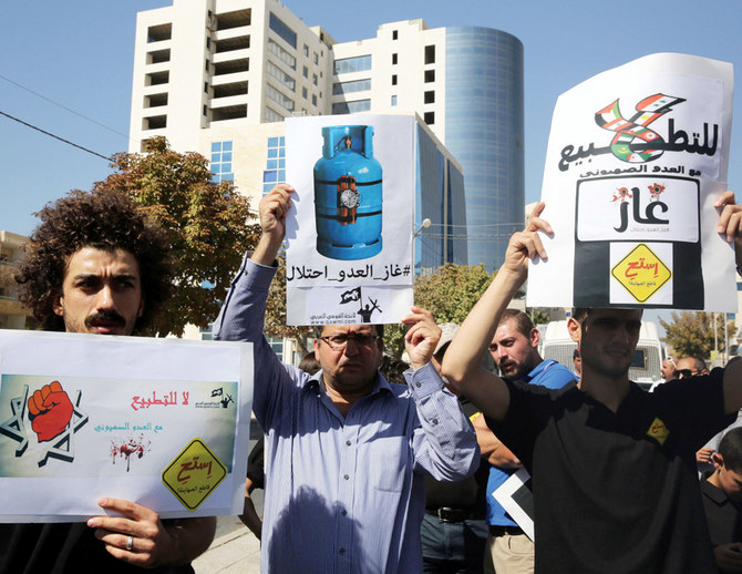 Jordanians hold placards during a demonstration in Amman against an agreement by Jordan to buy natural gas from Israel for 15 years. (AFP/File)