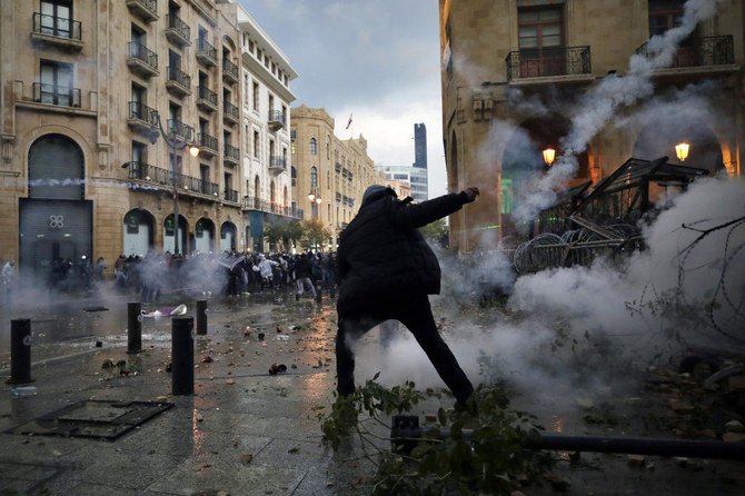 Anti-government protesters clash with the riot police, during a protest at a road leading to the parliament building in Beirut, Lebanon, Saturday, Jan. 18, 2020. Riot police fired tears gas and sprayed protesters with water cannons near parliament building to disperse thousands of people. (AP)