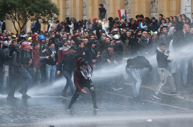 Anti-government protesters clash with the riot police, during a protest at a road leading to the parliament building in Beirut, Lebanon, Saturday, Jan. 18, 2020. Riot police fired tears gas and sprayed protesters with water cannons near parliament building to disperse thousands of people. (AP)