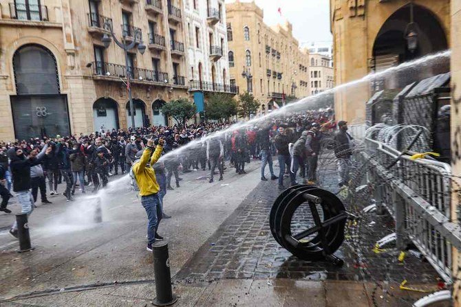 Anti-government protesters clash with the riot police, during a protest at a road leading to the parliament building in Beirut, Lebanon, Saturday, Jan. 18, 2020. Riot police fired tears gas and sprayed protesters with water cannons near parliament building to disperse thousands of people. (AP)