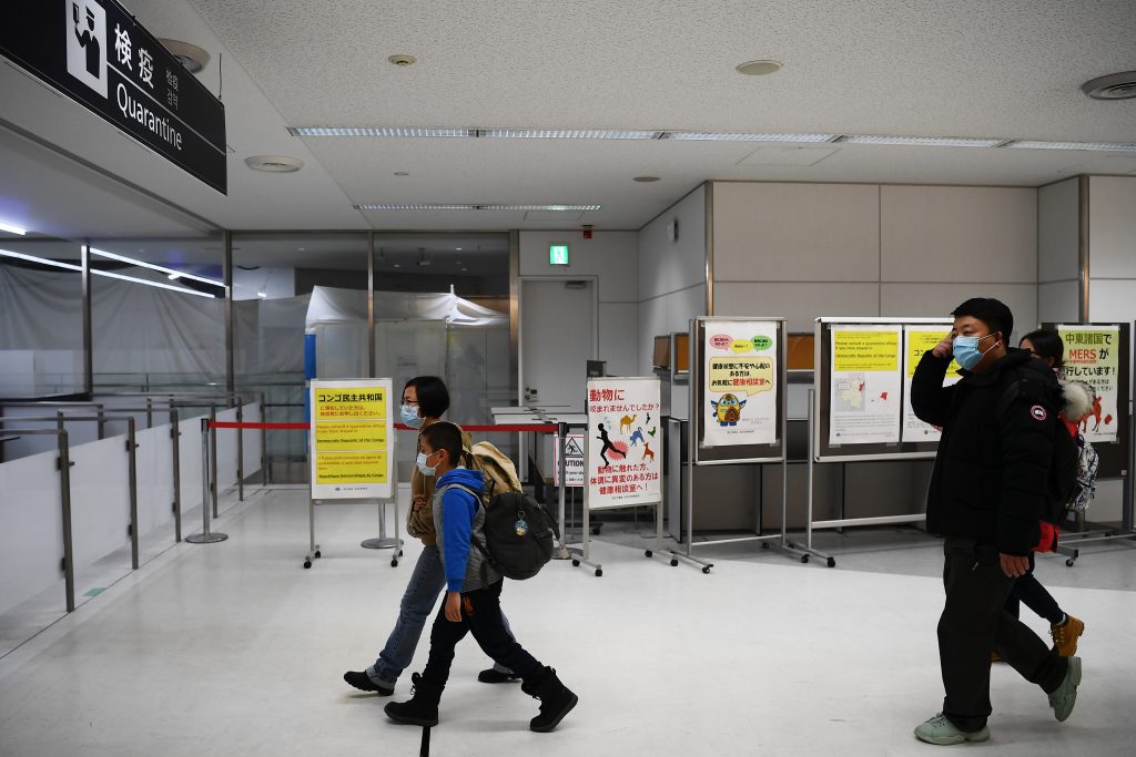 Passengers who arrived on one of the last flights from the Chinese city of Wuhan walk through a health screening station at Narita airport, Japan, Jan. 23, 2020. (AFP)