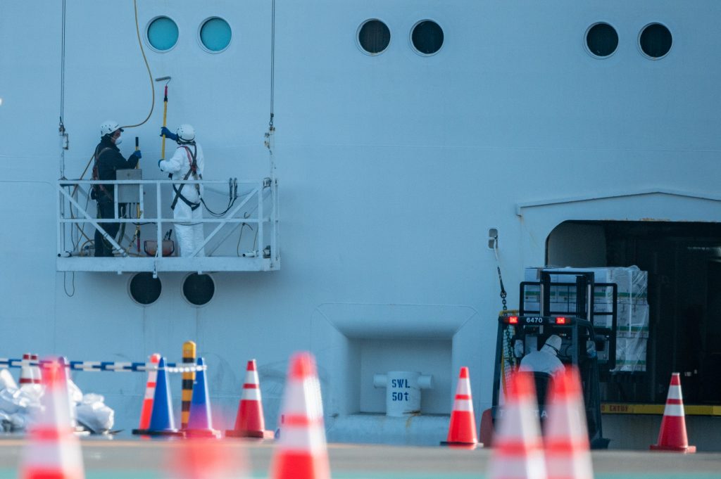 Crew members in protective clothing clean the the Diamond Princess cruise ship at Daikoku pier cruise terminal in Yokohama on February 24, 2020. (AFP)