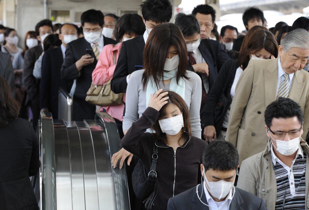 People wearing face masks arrive at a railway station on way to their offices in Kobe, Hyogo prefecture, May 18, 2009. 