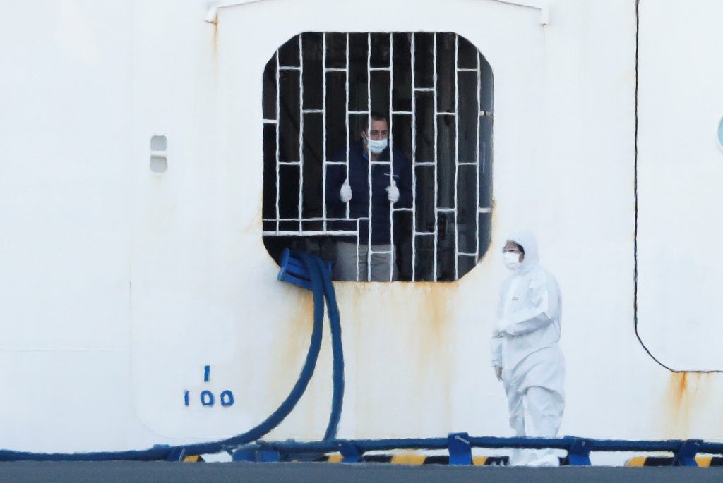 A crew member of the cruise ship Diamond Princess talks to a worker wearing protective gear standing near the vessel, Feb. 10, 2020. (Reuters)