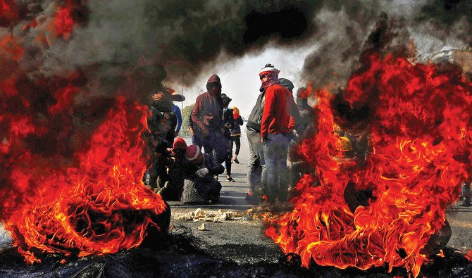 Anti-government protesters in Najaf cut off a road with burning tires during Wednesday’s demonstration against the new Iraqi prime minister. (AFP)