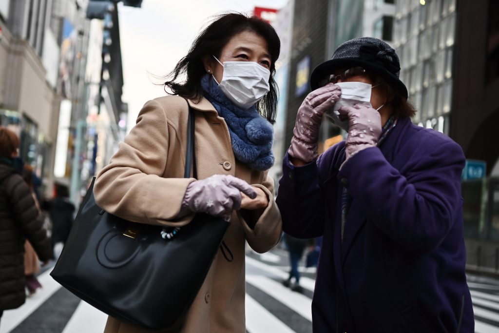 Pedestrians wearing protective masks walk on a street in Tokyo. (AFP)