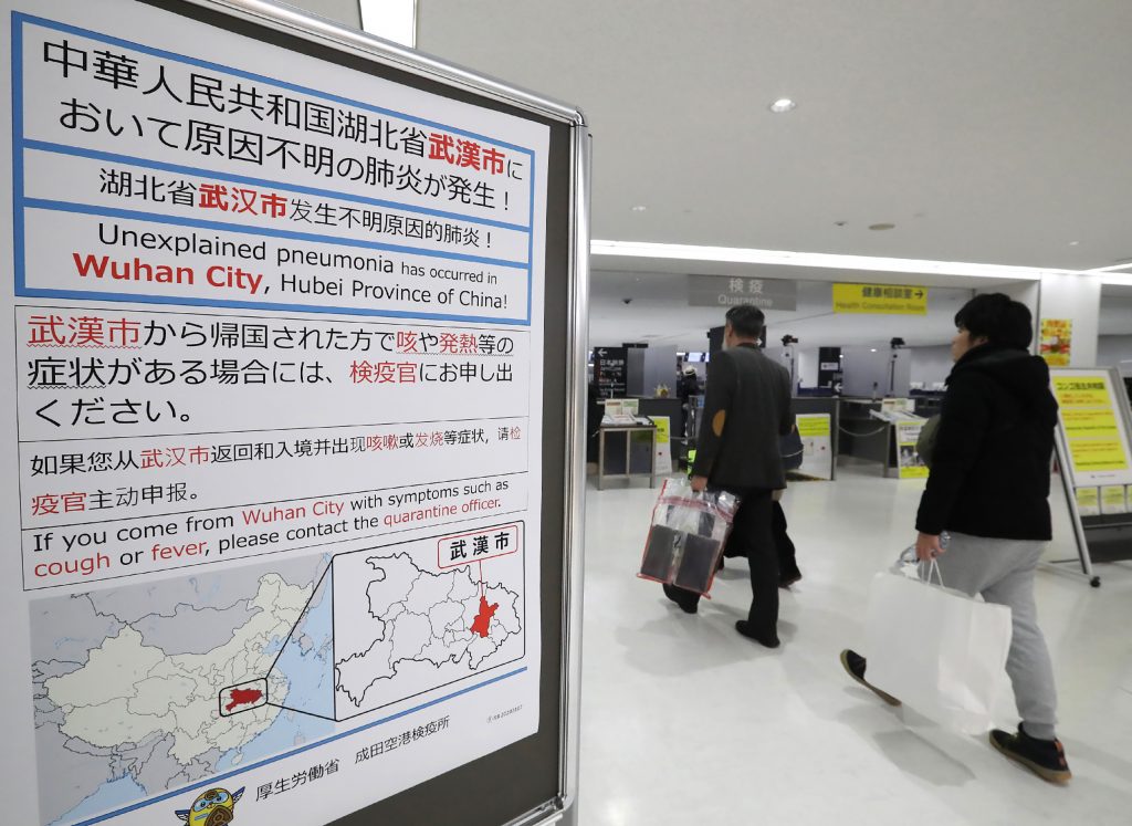 Passengers walk past a sign at Narita Airport in Chiba prefecture on Jan. 16, 2020. (AFP)