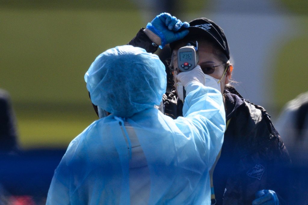  Workers in protective clothes measures the body temperature of a passenger disembarking from the Diamond Princess cruise ship, Feb. 21, 2020. (AFP)
