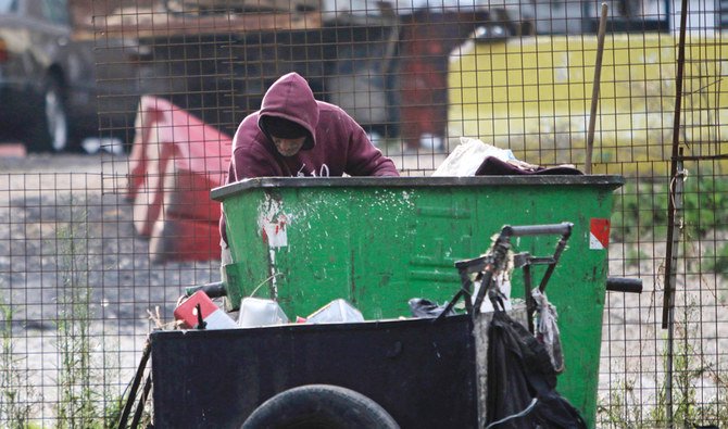 A man collects goods from a garbage bin in Lebanon's northern city of Tripoli on December 12, 2019. (AFP)