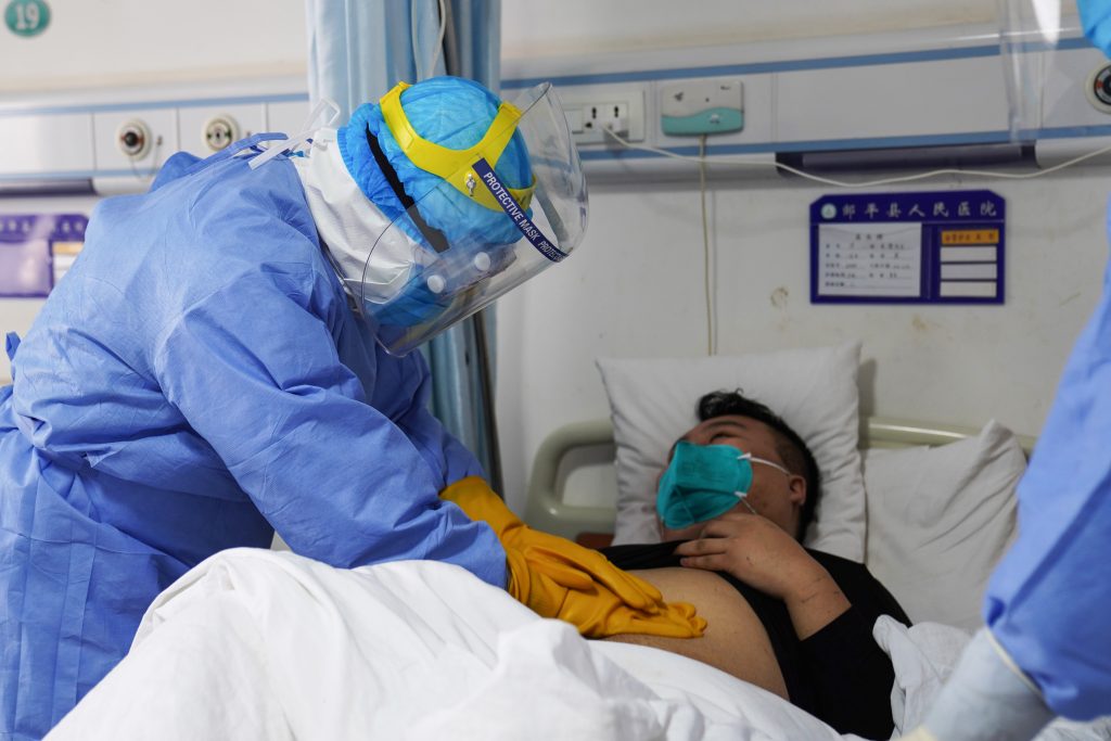 Medical staff member checking a patient infected by the novel coronavirus inside an isolation ward at a hospital. (AFP)