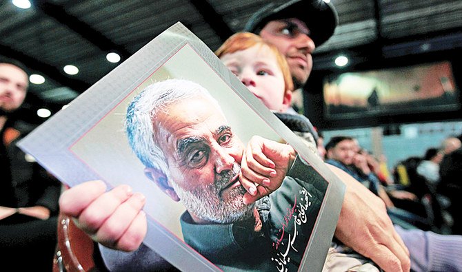 A man carries a child holding a picture of the late Iran’s Quds Force top commander Qassem Soleimani during a rally in Beirut, on Sunday. (Reuters)