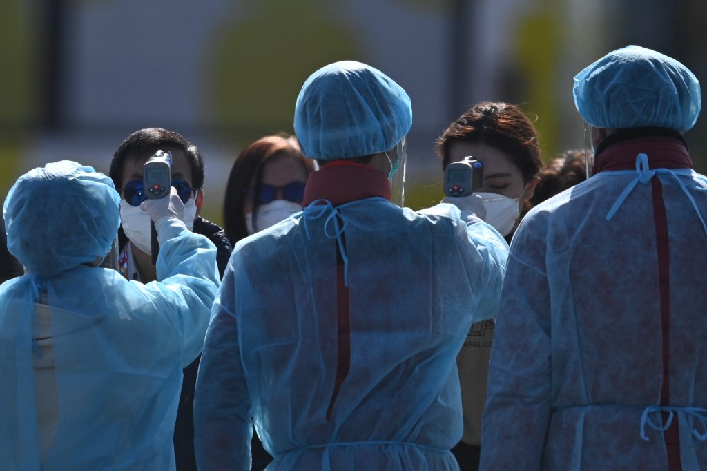 Workers in protective clothes measures the body temperature of a passenger disembarking from the Diamond Princess cruise ship in Yokohama, Feb. 21, 2020. (AFP)