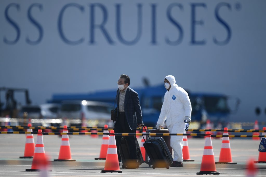 A passenger (L) disembarks from the Diamond Princess cruise ship at the Daikoku Pier Cruise Terminal in Yokohama, Feb. 19, 2020. 