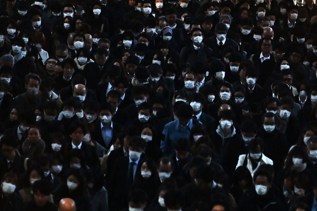 Mask-clad commuters make their way to work during morning rush hour at the Shinagawa train station in Tokyo on Feb. 28, 2020. (AFP)