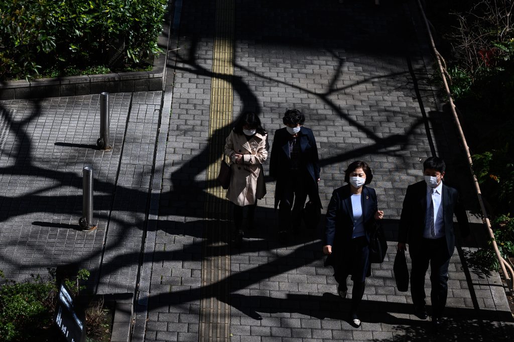 Pedestrians wearing face masks walk on a street in Tokyo on March 11, 2020. (AFP)
