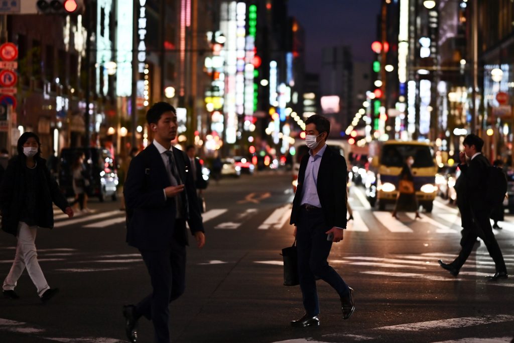 People wearing face masks, amid concerns of the COVID-19 coronavirus, crosses a street in Tokyo's Ginza area on March 18, 2020. (AFP)