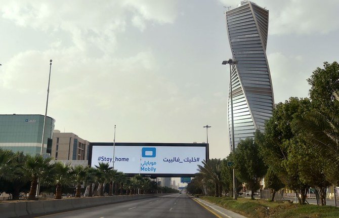 A picture taken on March 26, 2020, shows shows a huge billboard with says Stay Home in an empty King Fahad main street in the Saudi capital Riyadh, after the Kingdom began implementing an 11-hour nationwide curfew, on the day of an emergency G20 videoconference, to discuss a response to the COVID-19 crisis. (AFP)