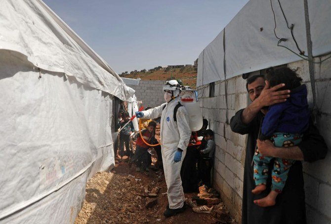 A member of the Syrian Civil Defense, also known as the “White Helmets,” disinfects a tent in the Kafr Lusin camp for the displaced by the border with Turkey, in Syria’s rebel-held northwestern province of Idlib, on March 24, 2020, as part of efforts to prevent the spread of coronavirus. (AFP)