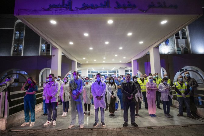 Health workers of government-run Rafik Hariri University Hospital, where most of the Lebanese coronavirus cases are treated, are saluted by Lebanese policemen in Beirut, Lebanon, Sunday, March 29, 2020. (AP)