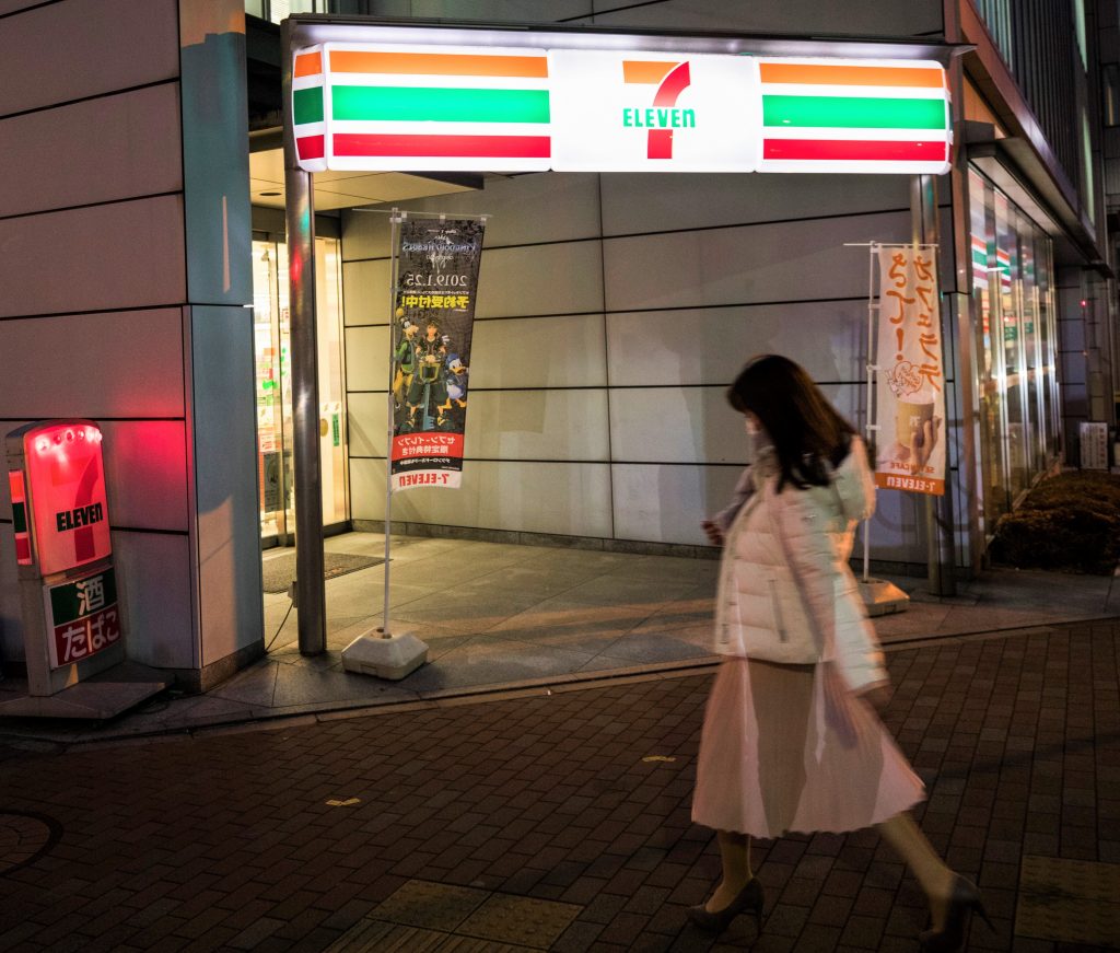 A woman walks past a 7-Eleven convenience store in Tokyo, Japan. (AFP)