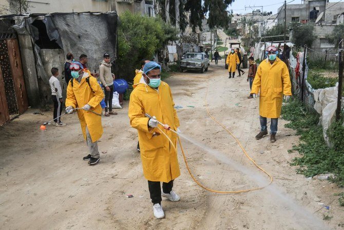 Palestinian volunteers wearing protective clothes and masks disinfect a street as a preventive measure against the spread of novel coronavirus, in Rafah in the southern Gaza Strip, on March 22, 2020. (AFP)