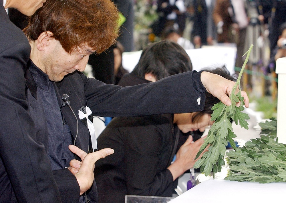 A patient of Minamata disease, caused by mercury poisoning, places a chrysanthemum on an altar at the 50th anniversary of one of the worst health disasters in Japanese history, at Minamata, Kumamoto prefecture, in northern Japan, 01 May 2006. (AFP/file)