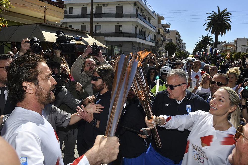 US actor Gerard Butler (left) passes the Olympic flame during the relay in Sparta on March 13, 2020 ahead of the Tokyo 2020 Olympic Games. (AFP)