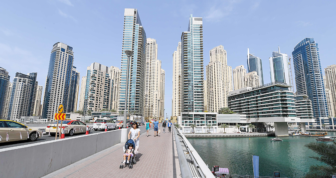 People walk on a bridge in Dubai. The stock markets in the region — which often track each other’s movements — went in different directions on Tuesday. (AFP)