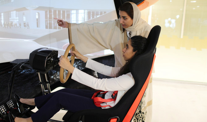 A driving instructor (back) teaches trainee Maria al-Faraj during a driving lesson on a 3D screen at Saudi Aramco Driving Center in Dhahran, Saudi Arabia, June 6, 2018. (REUTERS)
