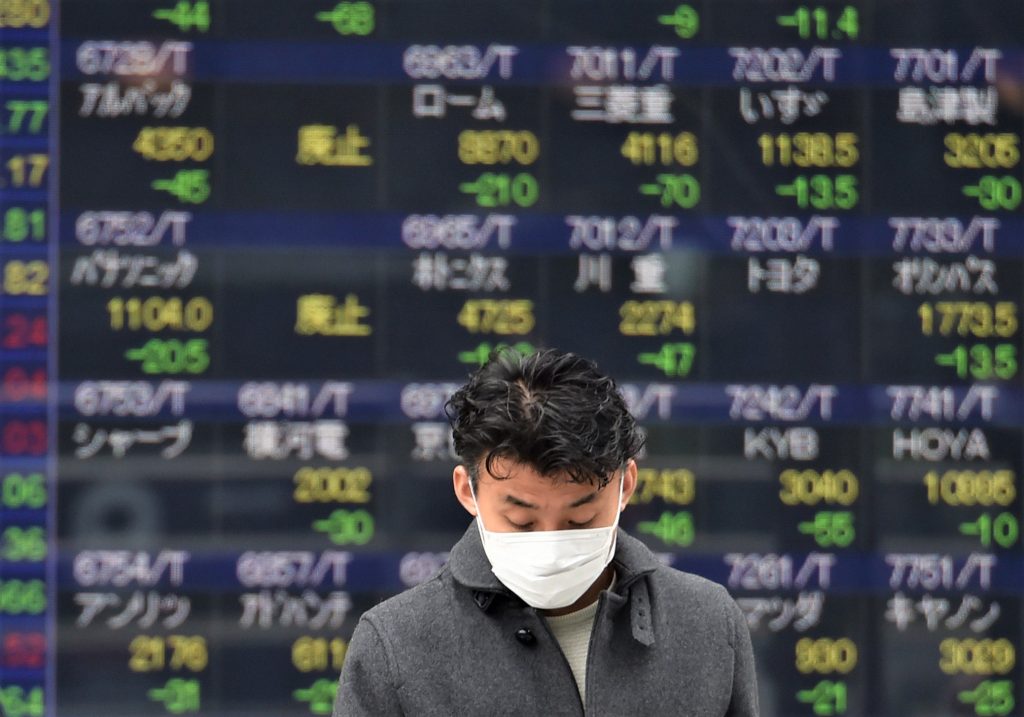 Pedestrians walk in front of an electric quotation board showing stock prices for Japanese companies on the Tokyo Stock Exchange in Tokyo, Jan. 27, 2020. (AFP)