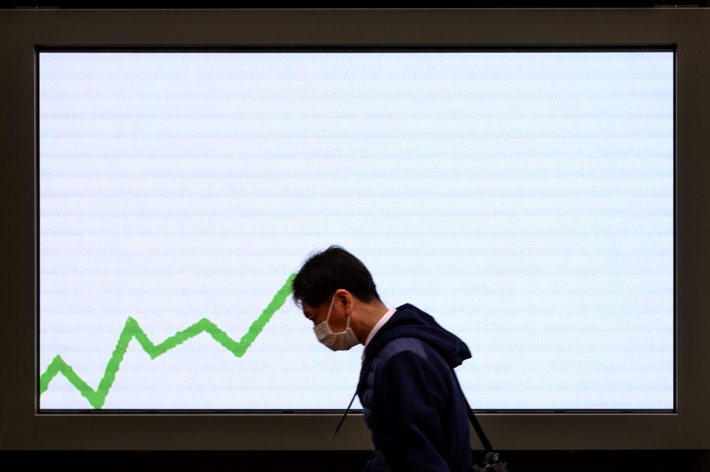 A pedestrian wearing a face mask, walks past an electronic board displaying an advertisement in Tokyo on Feb. 25, 2020. (AFP)