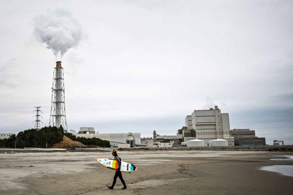 Koji Suzuki, a surfer and a surf shop owner, walking on the beach in front of a thermal power station after a surfing session in Minamisoma, Fukushima prefecture. (file photo/AFP)