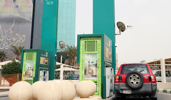 A man in a car withdraws money from an ATM outside the Saudi National Commercial Bank (NCB), after an outbreak of coronavirus, in Riyadh, Saudi Arabia, March 18, 2020. (REUTERS)