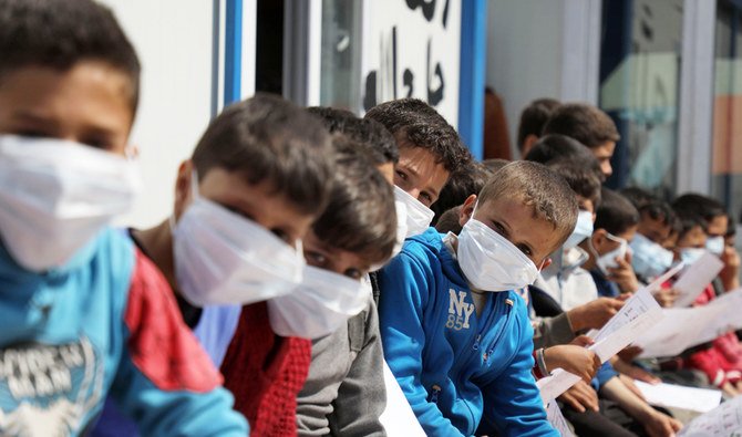 Displaced Syrian children and their parents attend a workshop organised by medical volunteer affiliated with a Turkish-registered Syrian relief organisation aimed at spreading awareness about COVID-19 coronavirus disease and precautions for its prevention, at a camp near the Syrian town of Atme close to the border with Turkey in Idlib province on March 16, 2020. (AFP)