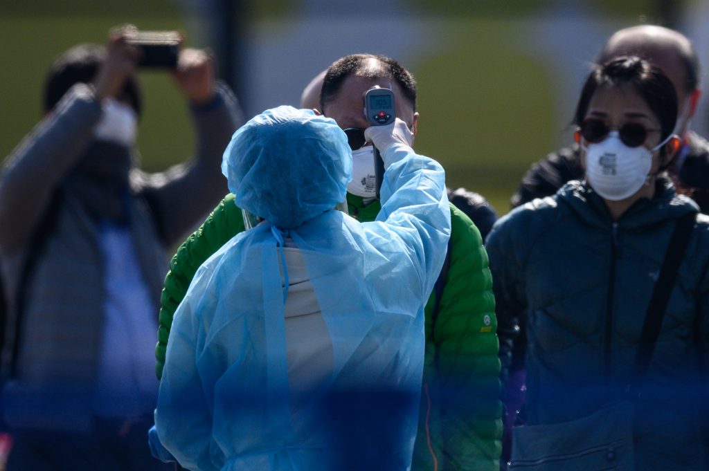 Workers in protective clothes measure people's body temperature due to fears of new COVID-19 coronavirus. (AFP)