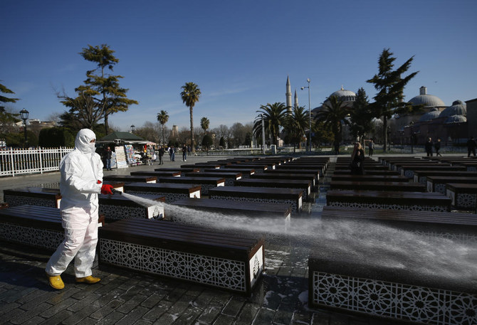 A municipality worker wearing a face mask and protective suits disinfects chairs outside the Sultan Ahmed Mosque amid the coronavirus outbreak, in Istanbul, Saturday, March 21, 2020. (AP)