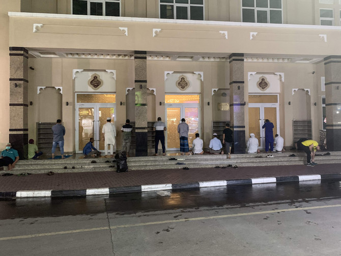 Muslim worshippers pray in front of the closed doors of a mosque in Dubai on March 21, 2020 amid the coronavirus COVID-19 pandemic. (AFP / Giuseppe Cacase)