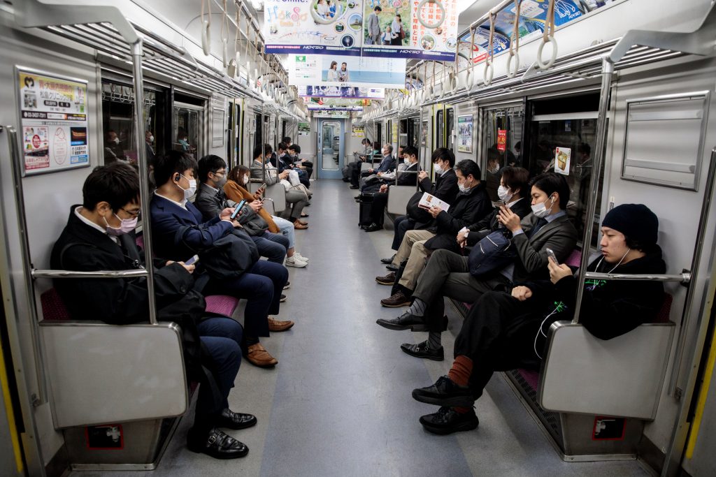 People wearing face masks amid concerns over the spread of the COVID-19 coronavirus, commute on a train in Tokyo on April 6, 2020. (AFP)