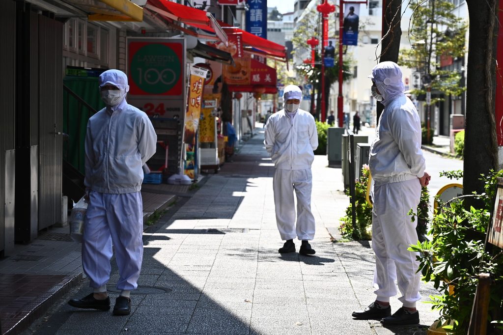 Employees of a restaurant wearing masks stand outside their eatery before it opens in the Chinatown area in Yokohama on April 9, 2020. (AFP)