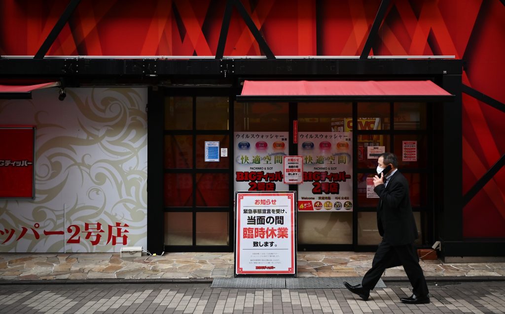 A man wearing a face mask walks in front of a closed pachinko in the Tokyo's Shinbashi area on April 24, 2020. (AFP)