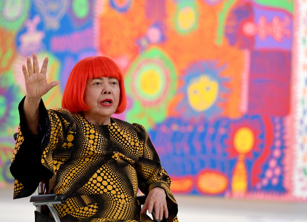 Japanese artist Yayoi Kusama waves at a photo session during a press preview of her exhibition titled 