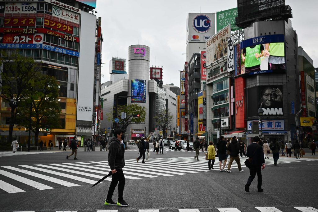 People wearing face masks cross an intersection usually filled with people in the Shibuya area in Tokyo on April 5, 2020.