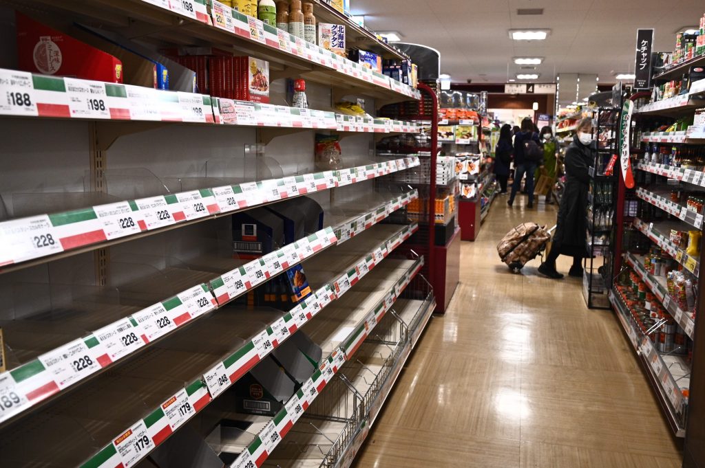 People shop near empty food shelves at a supermarket in Tokyo in April 6, 2020.