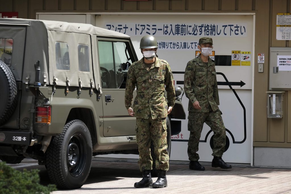 Military personnel walk around a hotel set to be used to accommodate COVID-19 coronavirus patients with light symptoms in Tokyo on April 7, 2020. Japan's Prime Minister Shinzo Abe will on April 7 declare a state of emergency in parts of the country, including Tokyo, over a spike in coronavirus infections. (AFP)