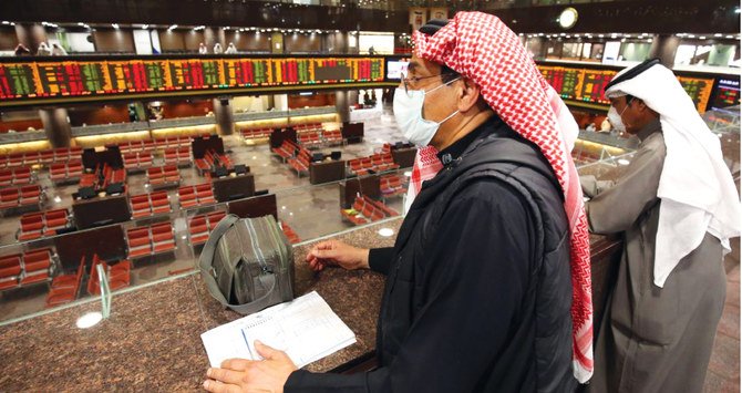 Kuwaiti traders wearing protective masks to guard against the coronavirus, follow the market at the Boursa Kuwait stock exchange in Kuwait City. AFP A trader walks by beneath a stock display board at the Dubai Stock Exchange in the United Arab Emirates, on March 8, 2020. Saudi’s stock exchange fell 6.5 percent and other Gulf markets tumbled to multi-year lows at the start of trading after OPEC and its allies failed to clinch a deal over oil production cuts. (AFP)