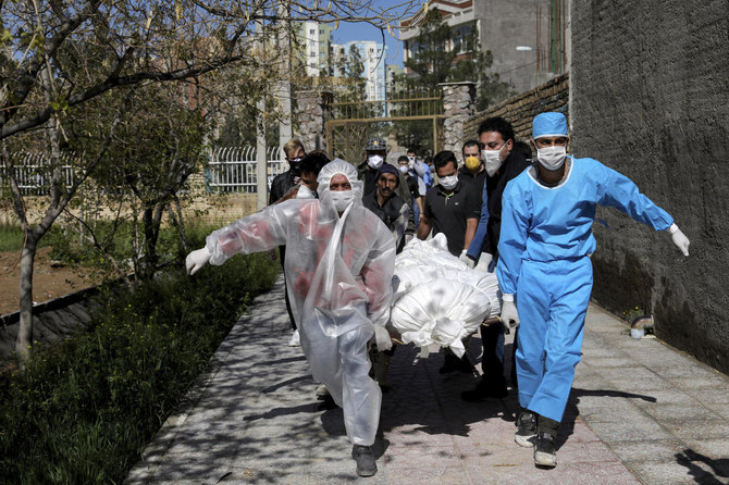 In this Monday, March 30, 2020 file photo, people carry the body of a victim who died after being infected with the new coronavirus at a cemetery just outside Tehran, Iran. Across the Middle East and parts of South Asia, bereaved families have faced traumatic restrictions on burying their dead amid the pandemic. (AP)