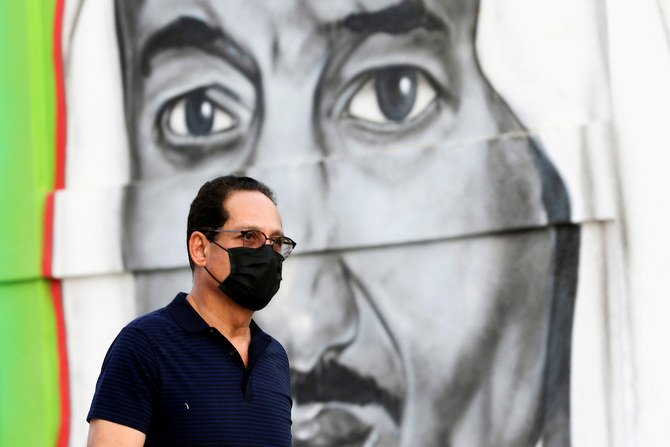 A Saudi man walks past a poster depicting Saudi King Salman bin Abdulaziz, after a curfew was imposed to prevent the spread of the coronavirus disease (COVID-19), in Riyadh, Saudi Arabia March 25, 2020. (Reuters)