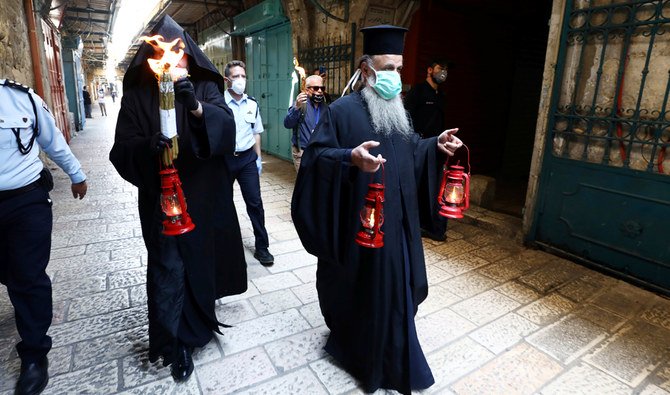 Orthodox Christian clergymen hold candlesstick and lamps as they deliver it following the Holy Fire ceremony that took place in the Church of the Holy Sepulchre in Jerusalem’s Old City amid the coronavirus disease (COVID-19) outbreak on Saturday. (Reuters)